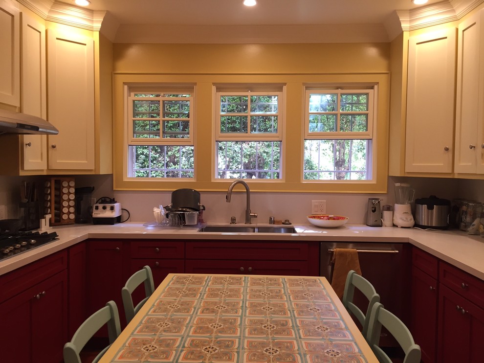 Example of a large southwest u-shaped dark wood floor eat-in kitchen design in Los Angeles with a double-bowl sink, recessed-panel cabinets, red cabinets, solid surface countertops, stainless steel appliances and an island