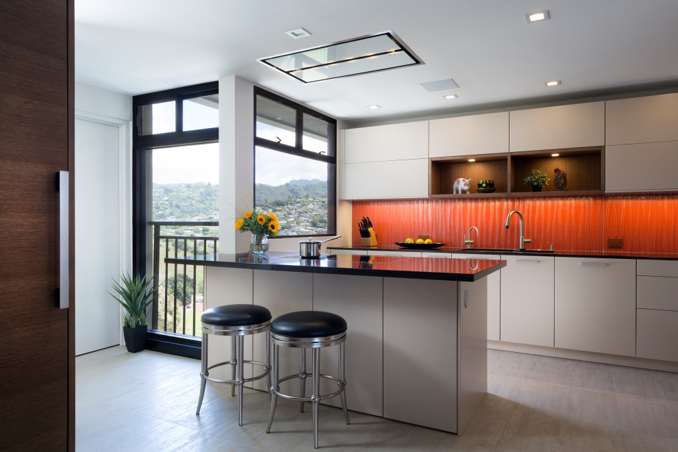 Design ideas for a medium sized modern kitchen pantry in Hawaii with a submerged sink, flat-panel cabinets, beige cabinets, engineered stone countertops, orange splashback, glass sheet splashback, integrated appliances, porcelain flooring, a breakfast bar, grey floors and black worktops.