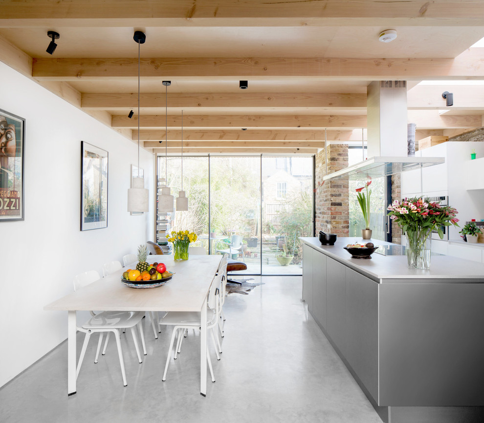 Foto på ett mellanstort funkis kök och matrum, med betonggolv, grått golv, släta luckor, vita skåp och en köksö