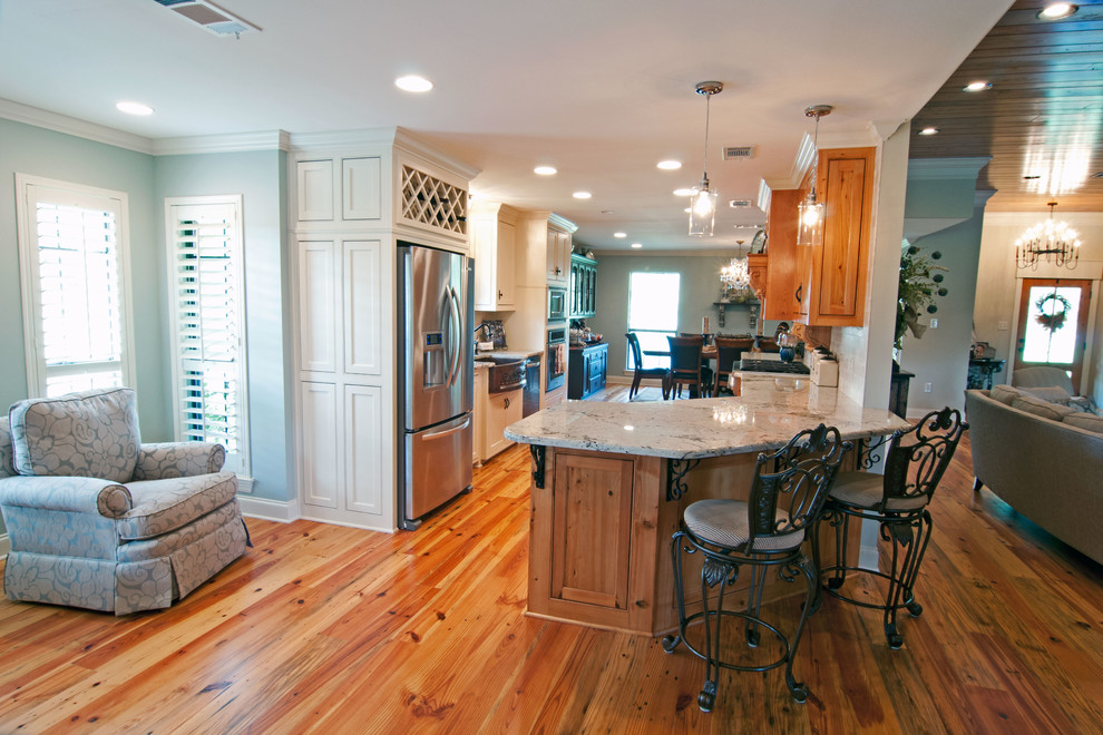 Example of a large classic galley light wood floor eat-in kitchen design in New Orleans with a farmhouse sink, light wood cabinets, granite countertops, beige backsplash, stone tile backsplash, stainless steel appliances, a peninsula and beaded inset cabinets