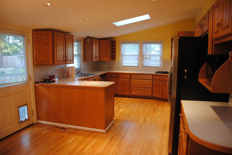 Example of a large country l-shaped light wood floor eat-in kitchen design in Other with an undermount sink, raised-panel cabinets, white cabinets, granite countertops, white backsplash, glass sheet backsplash, stainless steel appliances and a peninsula