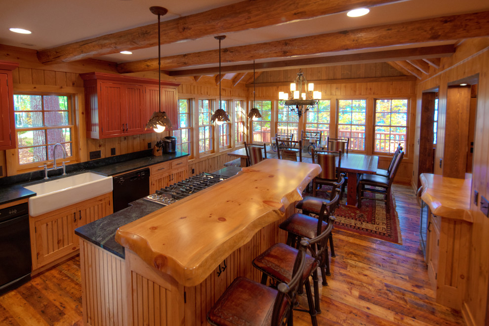 Exempel på ett mellanstort rustikt kök, med en rustik diskho, luckor med profilerade fronter, skåp i ljust trä, bänkskiva i täljsten, brunt stänkskydd, stänkskydd i trä, svarta vitvaror, mellanmörkt trägolv, en köksö och brunt golv