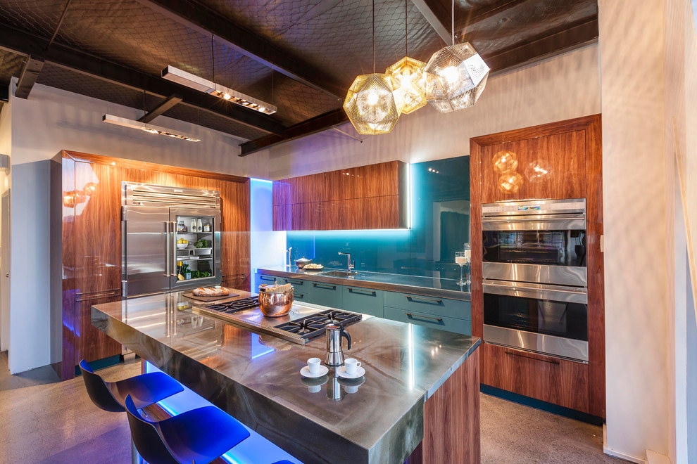 Foto di una cucina moderna di medie dimensioni con lavello integrato, ante lisce, ante beige, top in onice, paraspruzzi blu, paraspruzzi con lastra di vetro, elettrodomestici in acciaio inossidabile, pavimento in cemento e pavimento beige