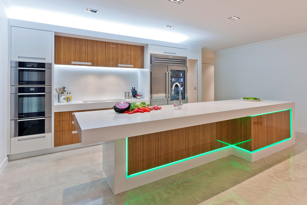 Medium sized modern galley kitchen/diner in Los Angeles with an integrated sink, flat-panel cabinets, medium wood cabinets, engineered stone countertops, white splashback, stainless steel appliances, porcelain flooring, an island and beige floors.