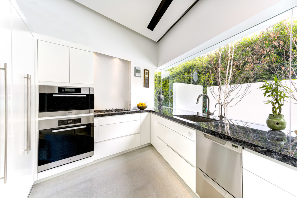 Idéer för ett stort modernt kök, med en undermonterad diskho, släta luckor, vita skåp, marmorbänkskiva, rostfria vitvaror och betonggolv