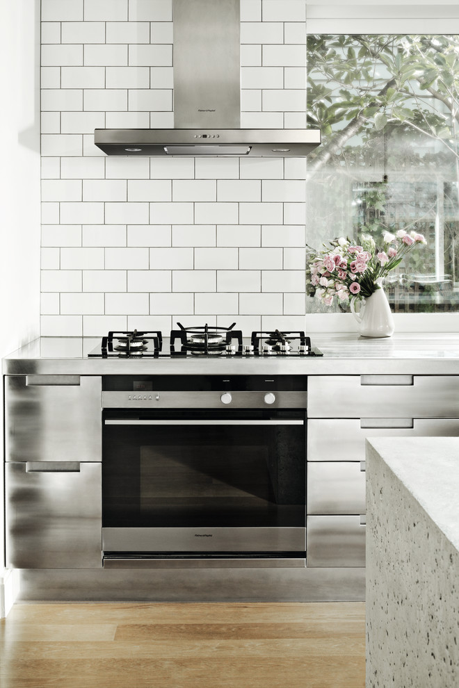 インダストリアルスタイルのおしゃれなキッチン (フラットパネル扉のキャビネット、ステンレスキャビネット、コンクリートカウンター、シルバーの調理設備、無垢フローリング、茶色い床) の写真