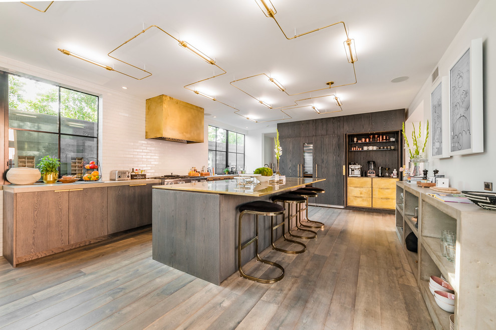 This is an example of an expansive contemporary single-wall kitchen/diner in Los Angeles with white splashback, an island, flat-panel cabinets, metro tiled splashback, integrated appliances, concrete worktops, grey cabinets, grey floors and medium hardwood flooring.