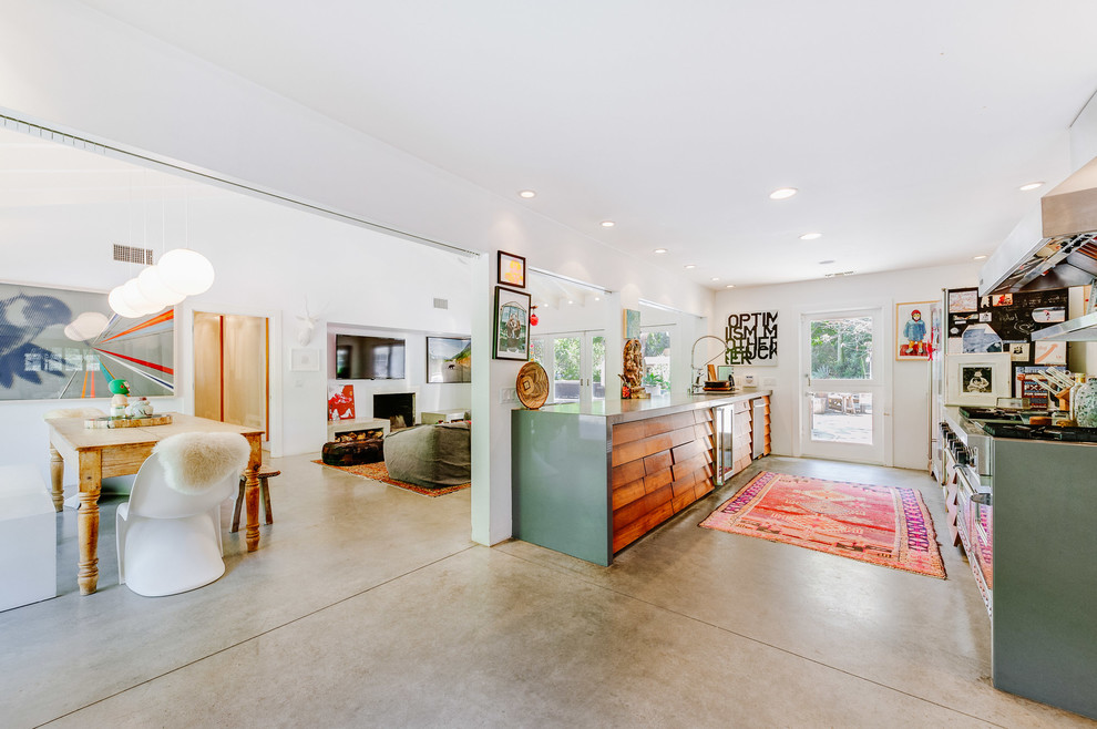 Inspiration for a mid-sized eclectic galley concrete floor open concept kitchen remodel in Los Angeles with louvered cabinets, medium tone wood cabinets, solid surface countertops, stainless steel appliances and a double-bowl sink