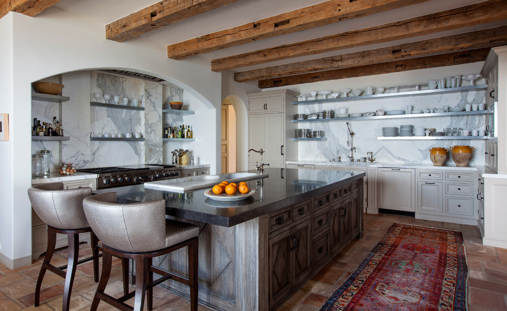 Geschlossene Mediterrane Küche mit Schrankfronten mit vertiefter Füllung, beigen Schränken, Küchenrückwand in Weiß, Terrakottaboden, Kücheninsel und Rückwand aus Marmor in Los Angeles