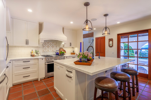 Cabinet color trends with classic all-white kitchen cabinets, marble countertop island, and warm terracotta floor tiles.