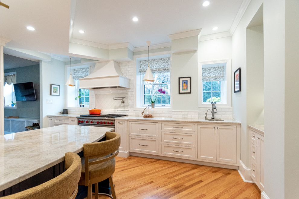 Exempel på ett stort klassiskt vit vitt kök och matrum, med en rustik diskho, luckor med profilerade fronter, vita skåp, bänkskiva i kvartsit, vitt stänkskydd, stänkskydd i porslinskakel, integrerade vitvaror, mellanmörkt trägolv, en köksö och brunt golv
