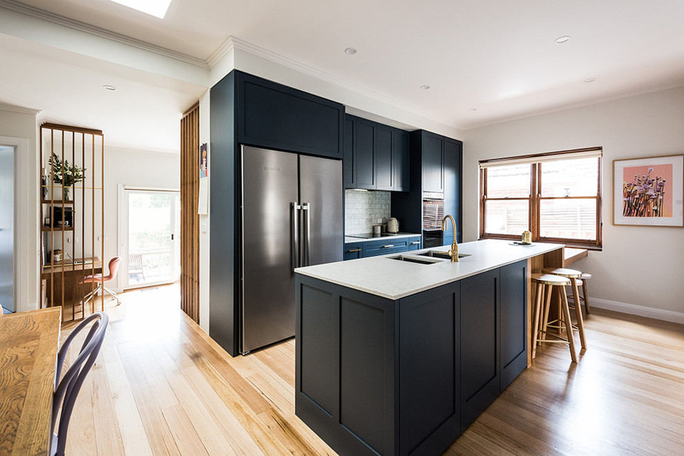 Eat-in kitchen - large transitional galley medium tone wood floor and brown floor eat-in kitchen idea in Melbourne with an undermount sink, shaker cabinets, blue cabinets, quartz countertops, gray backsplash, marble backsplash, stainless steel appliances and a peninsula