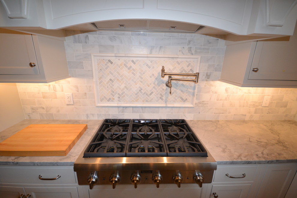 Example of a large transitional l-shaped medium tone wood floor kitchen pantry design in Philadelphia with an undermount sink, flat-panel cabinets, white cabinets, quartz countertops, white backsplash, stone tile backsplash, stainless steel appliances and an island