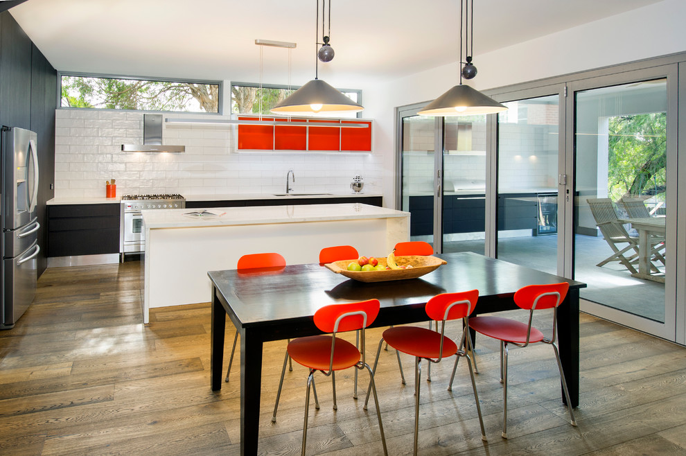 Photo of a contemporary l-shaped kitchen/diner in Melbourne with a double-bowl sink, flat-panel cabinets, orange cabinets, white splashback, stainless steel appliances, medium hardwood flooring and an island.