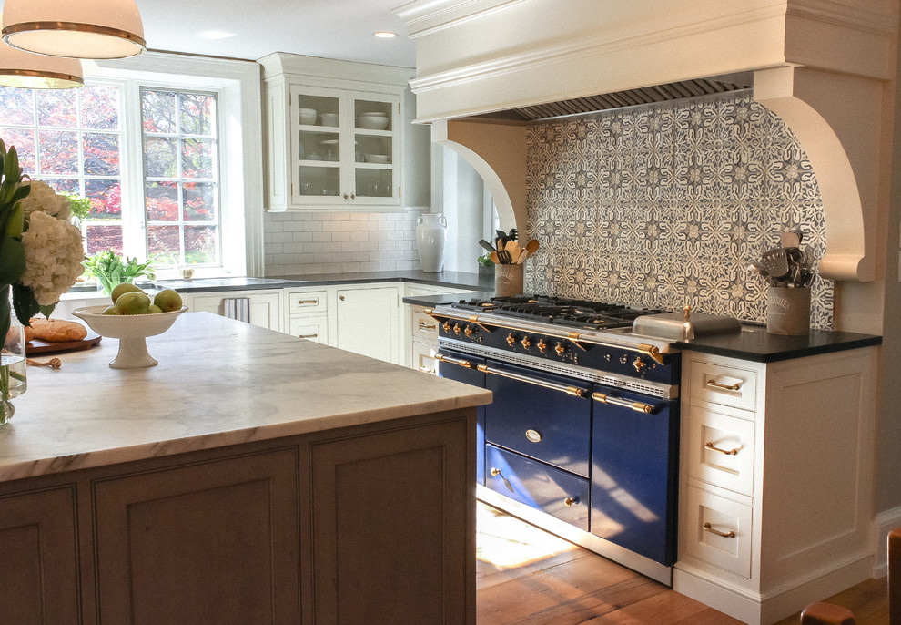 Inspiration for a large rural l-shaped kitchen/diner in Philadelphia with a belfast sink, beaded cabinets, white cabinets, marble worktops, multi-coloured splashback, cement tile splashback, integrated appliances, light hardwood flooring and an island.