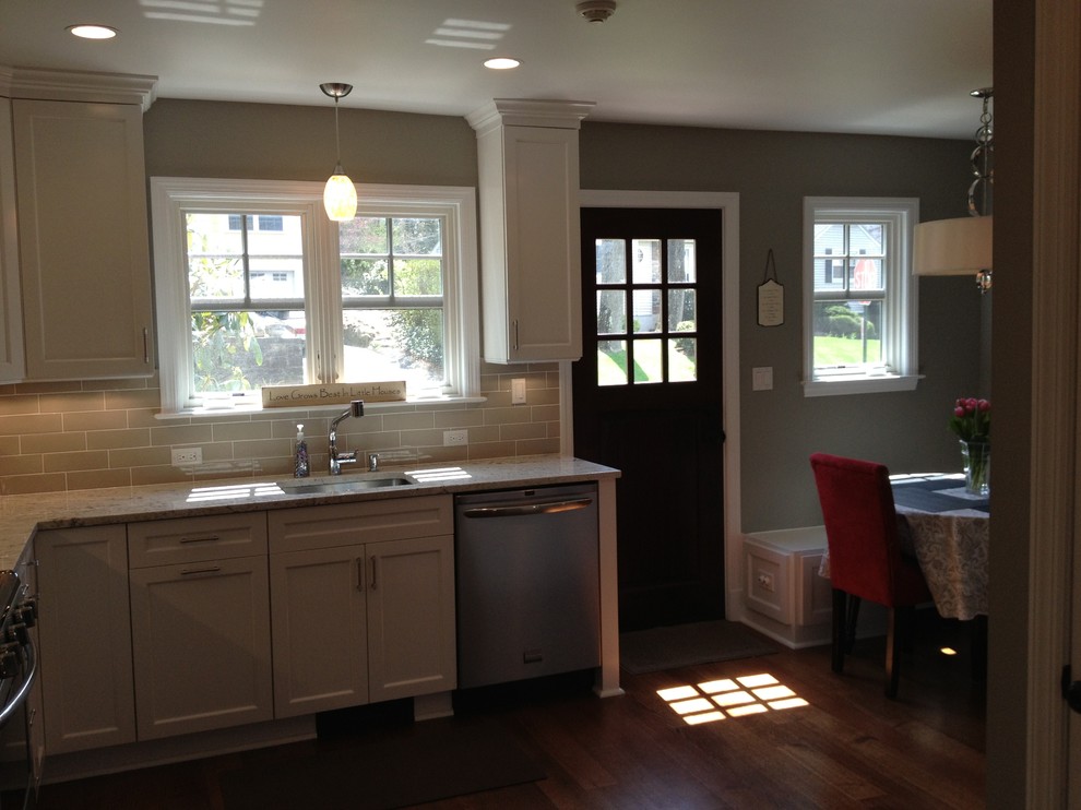Exempel på ett mellanstort klassiskt flerfärgad flerfärgat kök, med en undermonterad diskho, luckor med infälld panel, vita skåp, granitbänkskiva, beige stänkskydd, stänkskydd i keramik, rostfria vitvaror, mellanmörkt trägolv och brunt golv