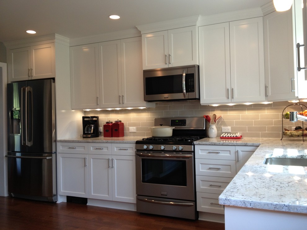 Klassisk inredning av ett mellanstort flerfärgad flerfärgat kök, med en undermonterad diskho, luckor med infälld panel, vita skåp, granitbänkskiva, beige stänkskydd, stänkskydd i keramik, rostfria vitvaror, mellanmörkt trägolv och brunt golv
