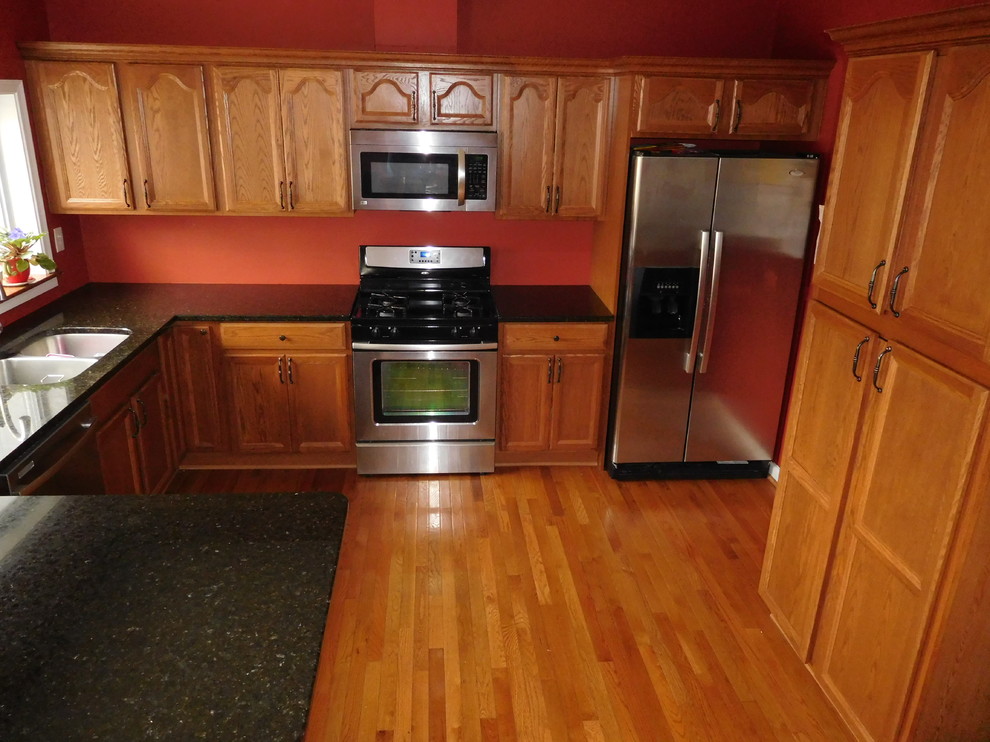 Idéer för att renovera ett mellanstort vintage kök, med en dubbel diskho, luckor med infälld panel, skåp i mellenmörkt trä, bänkskiva i kvarts, orange stänkskydd, rostfria vitvaror, mellanmörkt trägolv och en halv köksö