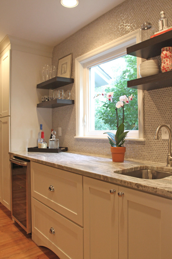 Klassisk inredning av ett kök, med en undermonterad diskho, öppna hyllor, bruna skåp, granitbänkskiva, brunt stänkskydd, stänkskydd i tunnelbanekakel, rostfria vitvaror, ljust trägolv och en köksö