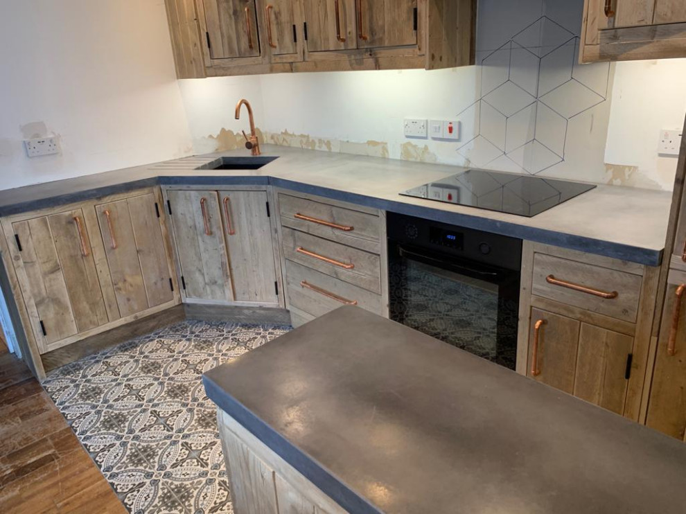 Inredning av ett rustikt grå grått kök med öppen planlösning, med skåp i slitet trä, bänkskiva i betong, klinkergolv i terrakotta och flerfärgat golv
