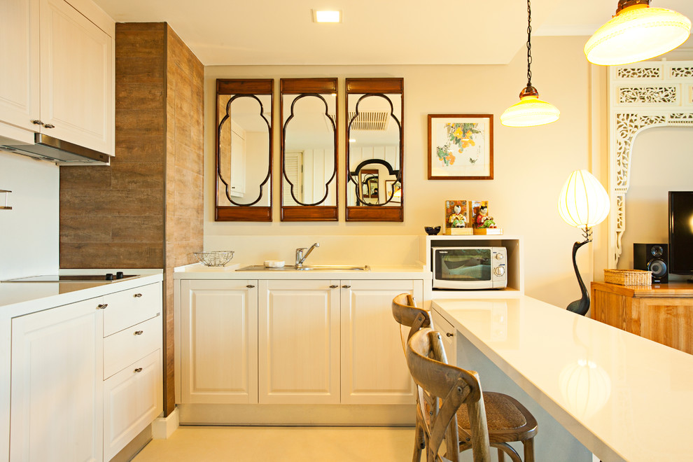 他の地域にあるアジアンスタイルのおしゃれなL型キッチン (レイズドパネル扉のキャビネット、白いキャビネット、白いキッチンパネル) の写真