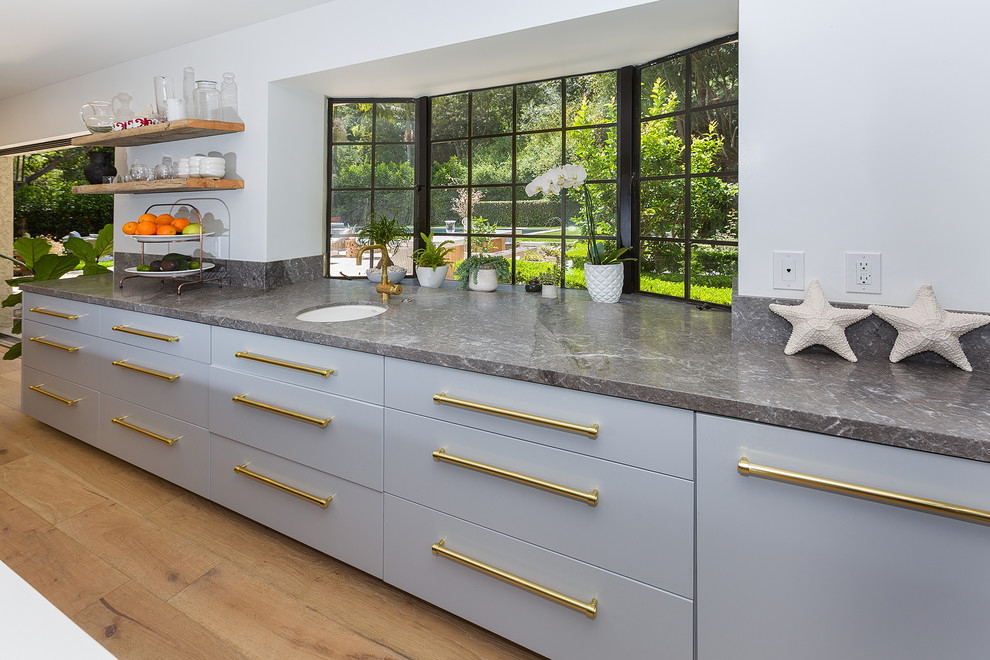 Example of a large transitional galley light wood floor enclosed kitchen design in Los Angeles with an integrated sink, flat-panel cabinets, gray cabinets, quartz countertops, stainless steel appliances and an island