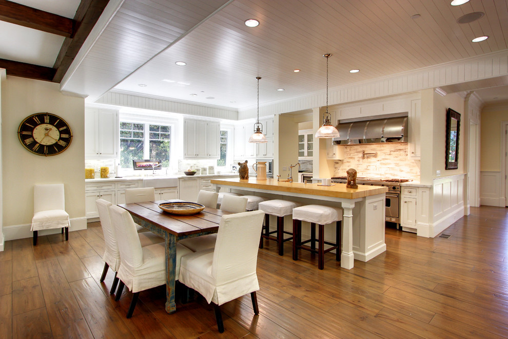 Example of a classic kitchen design in Los Angeles with wood countertops, a farmhouse sink, white cabinets and stainless steel appliances
