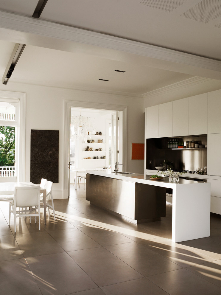 Ejemplo de cocina comedor minimalista grande con fregadero bajoencimera, puertas de armario blancas, salpicadero metalizado y una isla