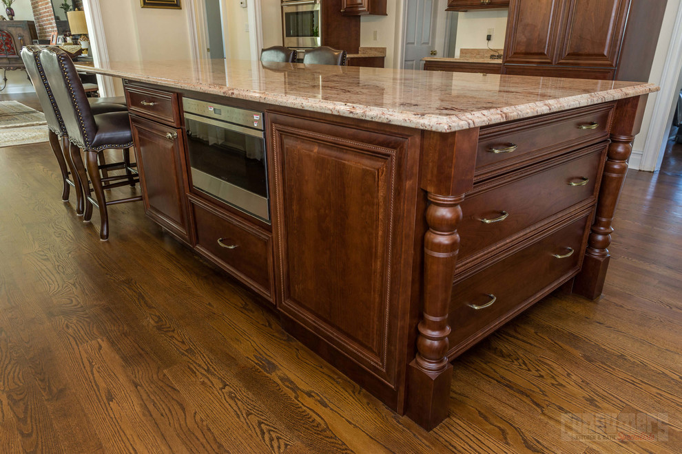 Example of a huge u-shaped plywood floor eat-in kitchen design in New York with a farmhouse sink, raised-panel cabinets, brown cabinets, beige backsplash, stainless steel appliances and an island