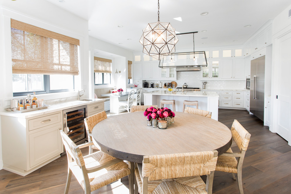 Example of a beach style medium tone wood floor and brown floor eat-in kitchen design in Los Angeles with medium tone wood cabinets, white backsplash, porcelain backsplash, stainless steel appliances and an island