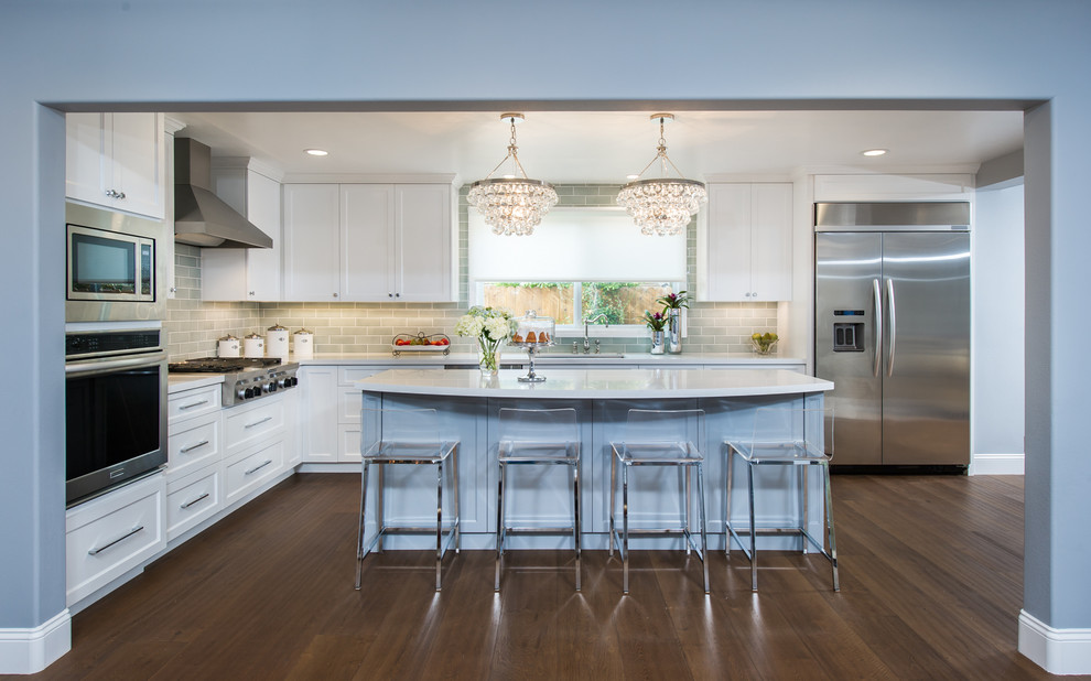 Inspiration for a mid-sized transitional l-shaped medium tone wood floor eat-in kitchen remodel in Los Angeles with a double-bowl sink, recessed-panel cabinets, white cabinets, quartz countertops, gray backsplash, ceramic backsplash, stainless steel appliances and an island