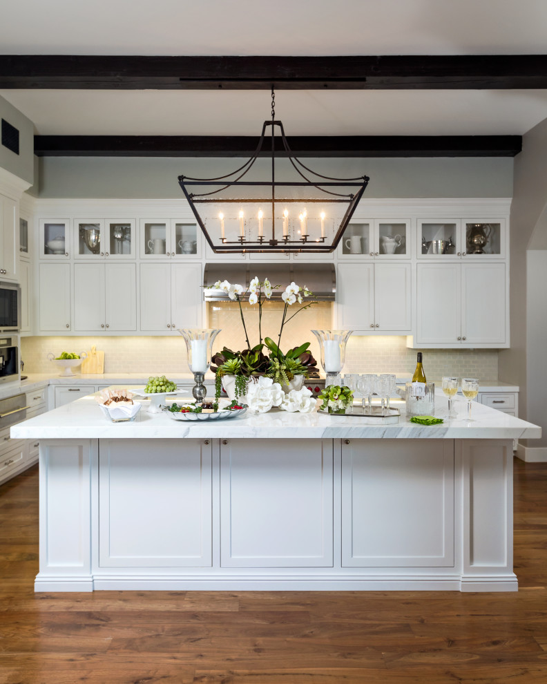 Inspiration for a large mediterranean l-shaped medium tone wood floor, brown floor and exposed beam kitchen remodel in Los Angeles with shaker cabinets, white cabinets, beige backsplash, stainless steel appliances, an island and gray countertops