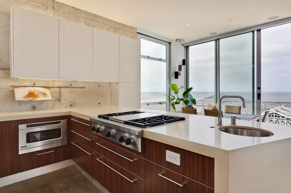 Bild på ett funkis kök, med släta luckor, vita skåp, rostfria vitvaror, en undermonterad diskho, bänkskiva i kvarts, betonggolv, en halv köksö och grått golv