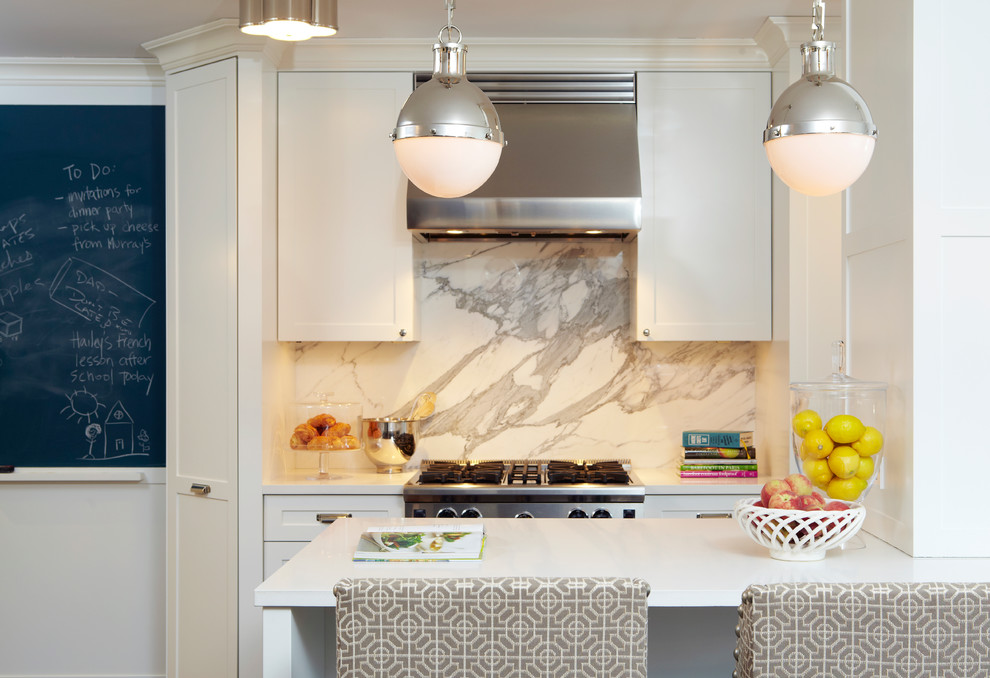 Photo of a contemporary kitchen in New York with shaker cabinets, white cabinets, white splashback and stainless steel appliances.