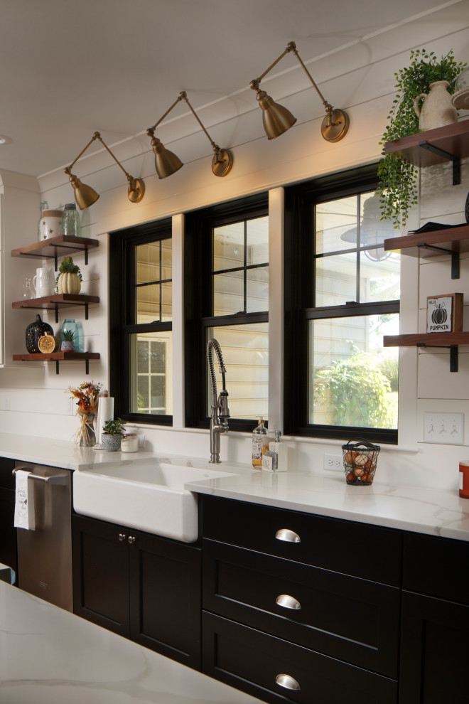 Example of a large cottage medium tone wood floor and brown floor eat-in kitchen design in Other with a farmhouse sink, shaker cabinets, black cabinets, quartz countertops, white backsplash, shiplap backsplash, stainless steel appliances, an island and white countertops