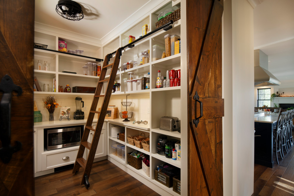 Foto på ett stort lantligt vit kök och matrum, med en rustik diskho, skåp i shakerstil, svarta skåp, bänkskiva i kvarts, vitt stänkskydd, rostfria vitvaror, mellanmörkt trägolv, en köksö och brunt golv