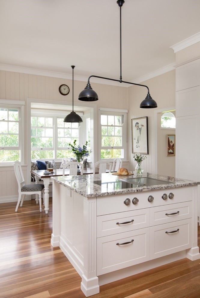 Immagine di un cucina con isola centrale minimal di medie dimensioni con ante di vetro, ante bianche, top in granito, paraspruzzi nero e top bianco