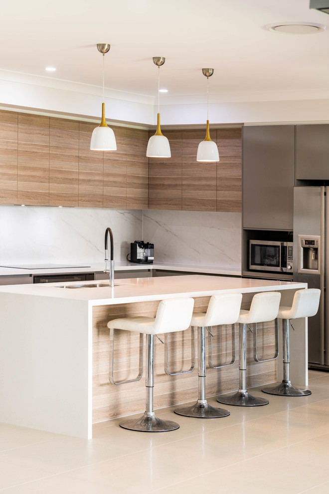 Moderne Küche in L-Form mit Unterbauwaschbecken, flächenbündigen Schrankfronten, hellbraunen Holzschränken, Küchenrückwand in Weiß, Küchengeräten aus Edelstahl, Kücheninsel, weißem Boden und weißer Arbeitsplatte in Brisbane