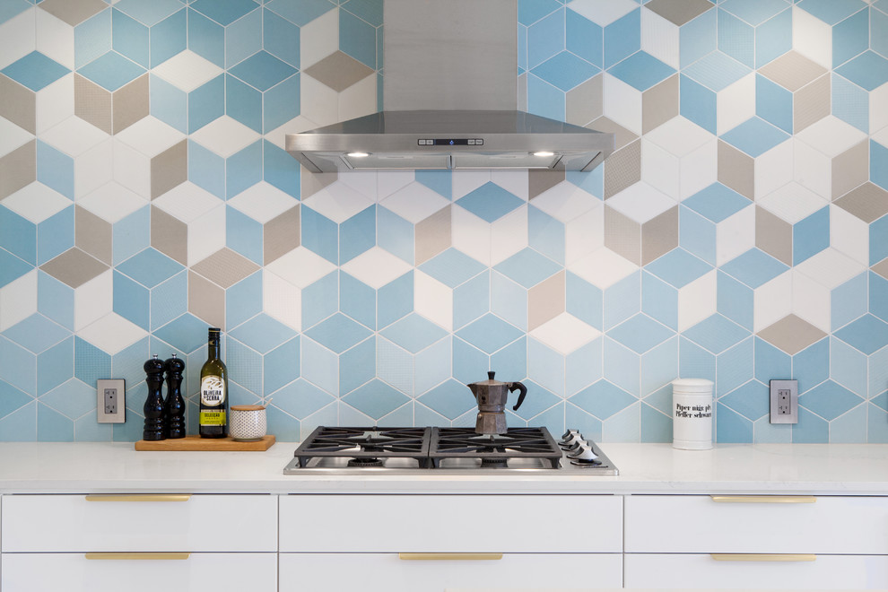 Photo of a modern l-shaped kitchen in Toronto with a submerged sink, flat-panel cabinets, white cabinets, engineered stone countertops, blue splashback, stainless steel appliances, light hardwood flooring and an island.