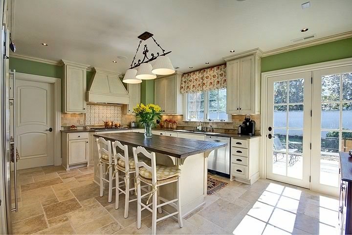 Cottage u-shaped eat-in kitchen photo in Nashville with an undermount sink, raised-panel cabinets, distressed cabinets, wood countertops, multicolored backsplash, stone tile backsplash and stainless steel appliances