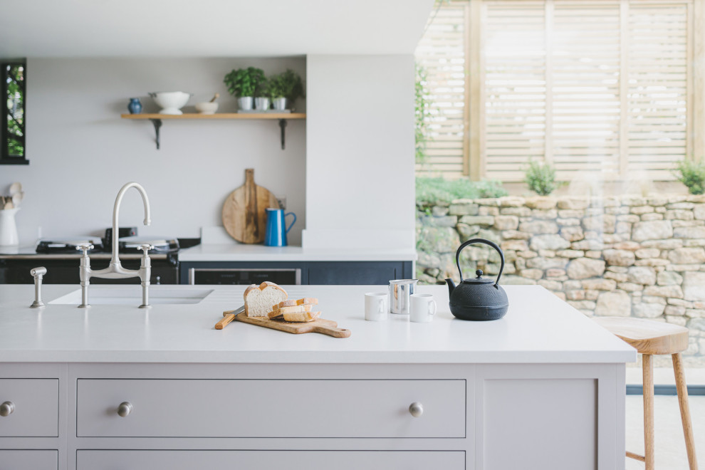 Inspiration for a large farmhouse l-shaped kitchen/diner in Gloucestershire with a built-in sink, shaker cabinets, blue cabinets, engineered stone countertops, stainless steel appliances, limestone flooring, an island and grey worktops.