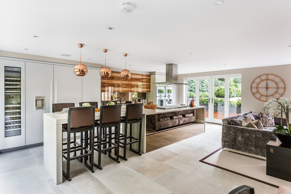 Photo of a contemporary galley open plan kitchen in Hampshire with flat-panel cabinets, white cabinets, mirror splashback, integrated appliances, an island, beige floors and white worktops.
