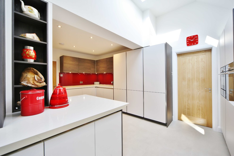 ロンドンにある高級な広いコンテンポラリースタイルのおしゃれなキッチン (フラットパネル扉のキャビネット、中間色木目調キャビネット、珪岩カウンター、赤いキッチンパネル、ガラス板のキッチンパネル、シルバーの調理設備) の写真