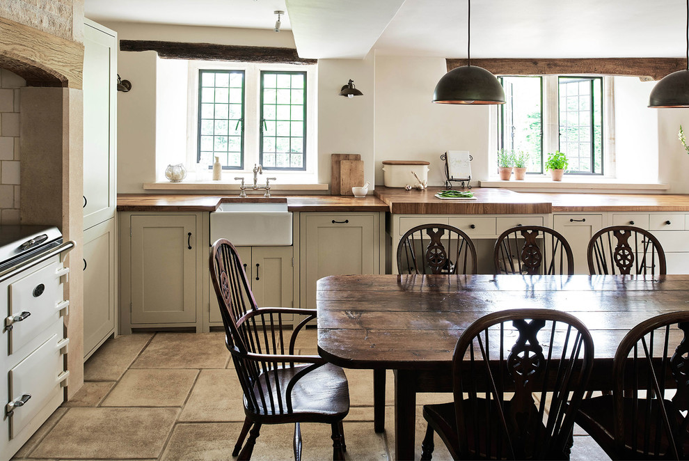 Photo of a large rural l-shaped kitchen/diner in Wiltshire with a belfast sink, shaker cabinets, wood worktops, beige splashback, ceramic splashback, limestone flooring and no island.