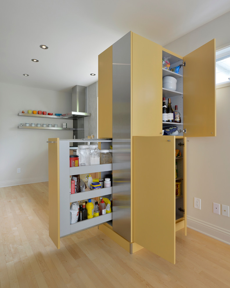 Modelo de cocina escandinava con armarios con paneles lisos, puertas de armario amarillas, electrodomésticos de acero inoxidable y suelo de madera clara
