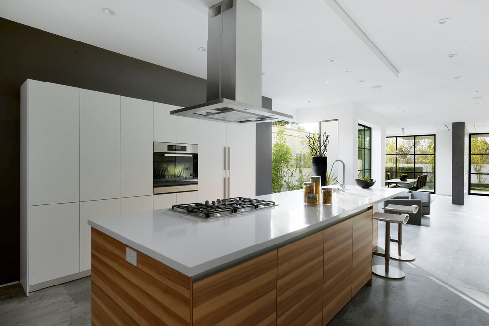 Large trendy l-shaped concrete floor eat-in kitchen photo in Los Angeles with an undermount sink, flat-panel cabinets, white cabinets, solid surface countertops, stainless steel appliances and an island