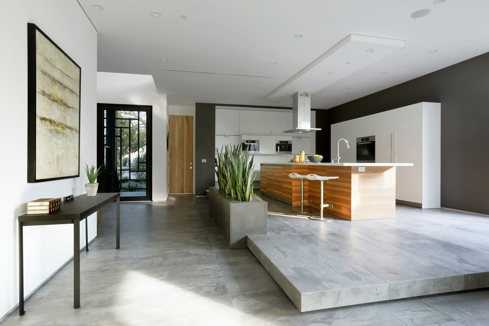 Inspiration for a large contemporary l-shaped concrete floor eat-in kitchen remodel in Los Angeles with an undermount sink, flat-panel cabinets, white cabinets, solid surface countertops, stainless steel appliances and an island