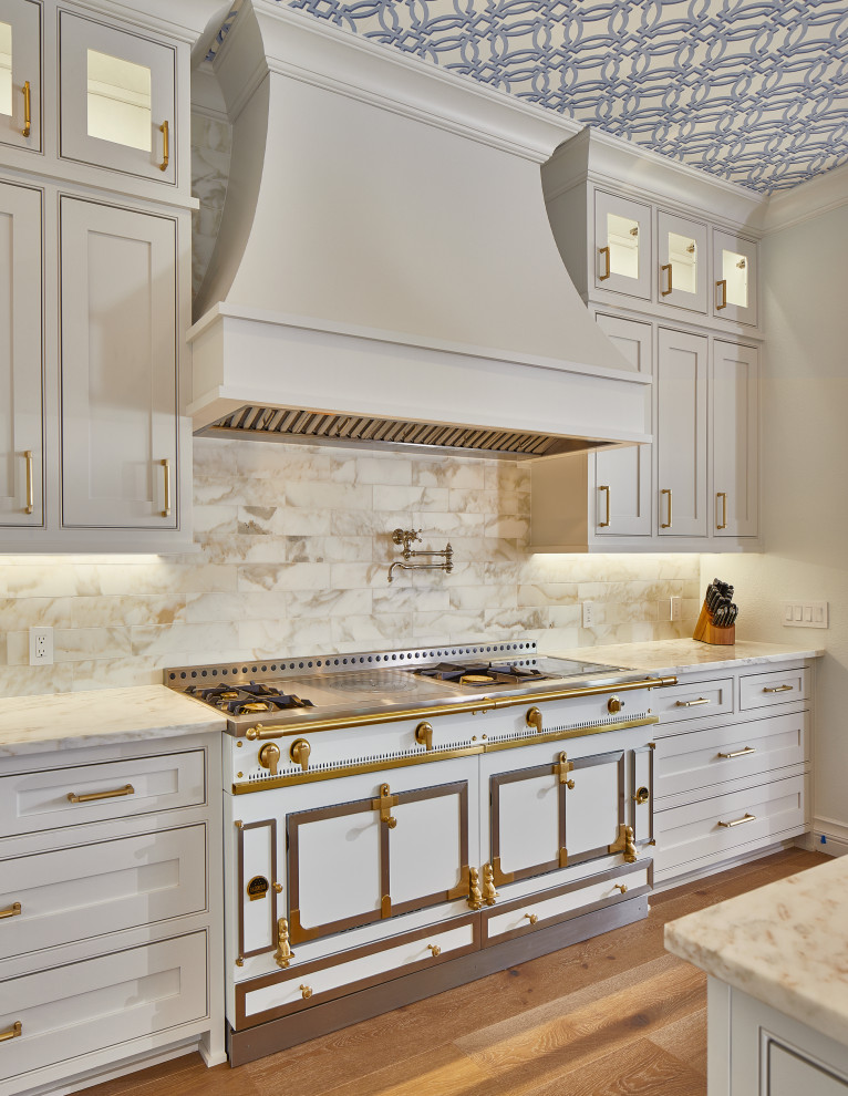 Foto di un cucina con isola centrale classico con lavello sottopiano, ante con riquadro incassato, ante bianche, top in marmo, paraspruzzi in marmo e parquet chiaro