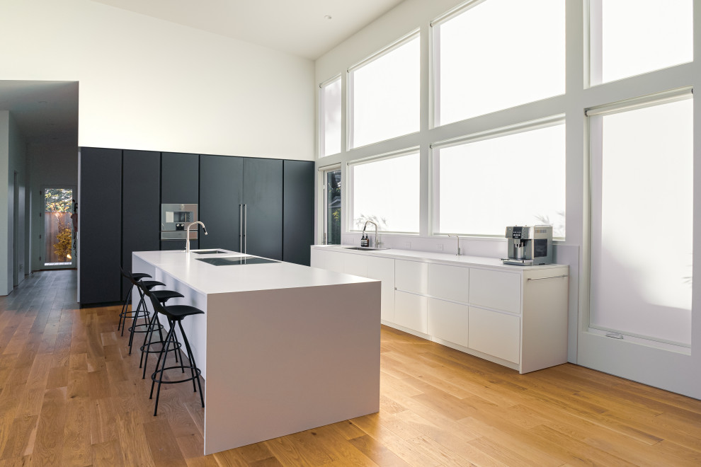 Inspiration for a huge modern light wood floor and brown floor open concept kitchen remodel in Portland with an undermount sink, flat-panel cabinets, white cabinets, quartz countertops, white backsplash, quartz backsplash, paneled appliances, an island and white countertops