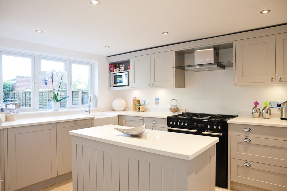 Traditional grey and cream kitchen in Berkshire with a belfast sink, shaker cabinets, beige cabinets and black appliances.